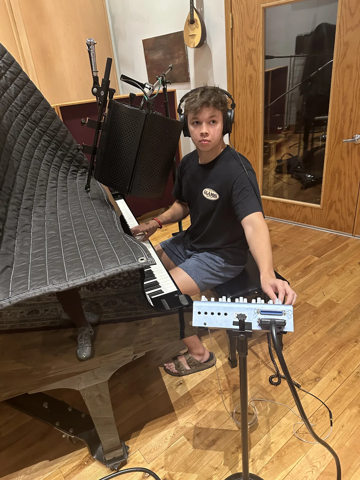 Max Cooper III at a piano in a recording studio wearing headphones